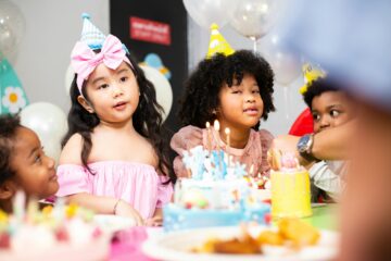 Group of little kids in party hat with birthday cake